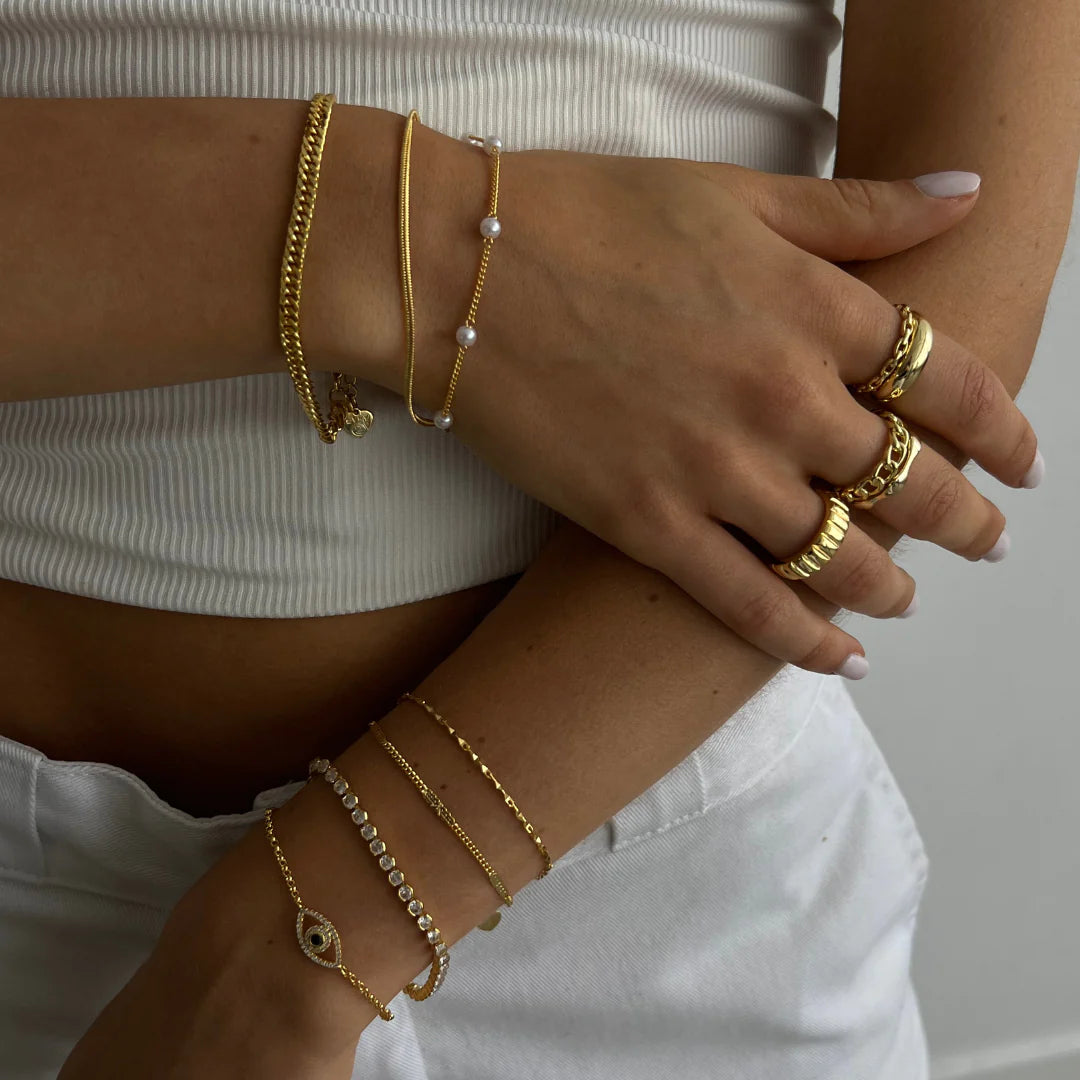 a woman wearing a white top and gold bracelets